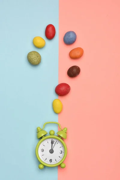 Green alarm clock with colorful dragee — Stock Photo, Image