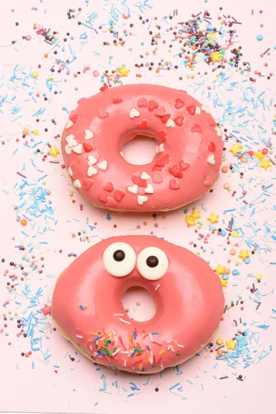 Grappige geglazuurde donuts op roze achtergrond — Stockfoto