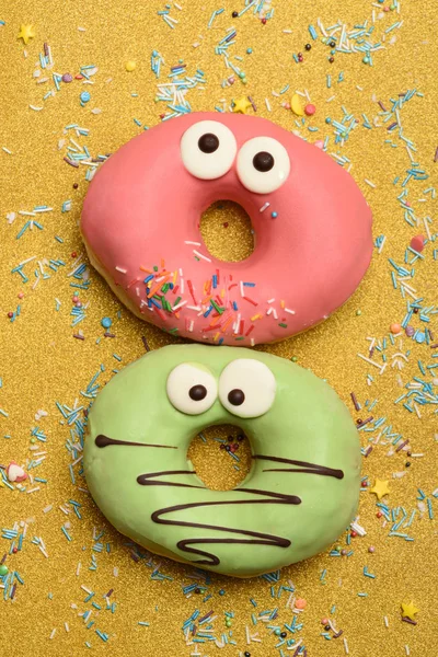 Grappige geglazuurde donuts op gouden achtergrond — Stockfoto