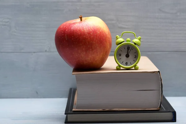 Böcker, rött äpple och väckarklocka — Stockfoto
