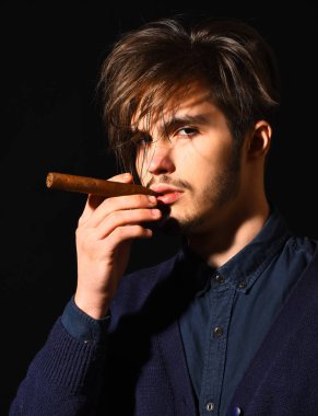 Ciddi sakallı adam puro içiyor.