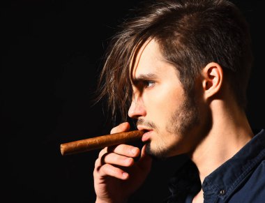 Ciddi sakallı adam puro içiyor.