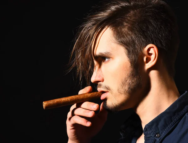 Ciddi sakallı adam puro içiyor.