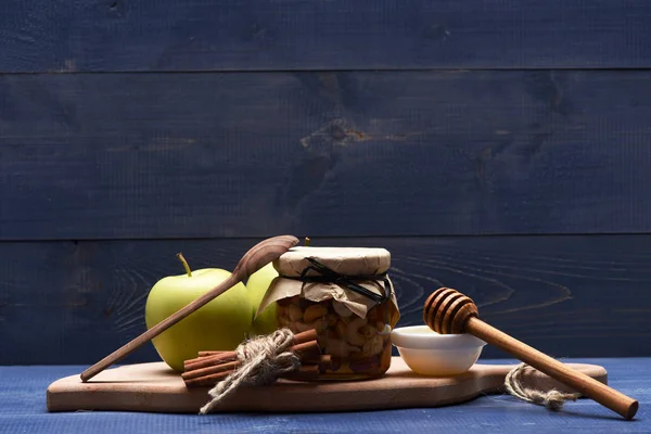 Manzanas, nueces en tarro de vidrio en tabla de cortar — Foto de Stock