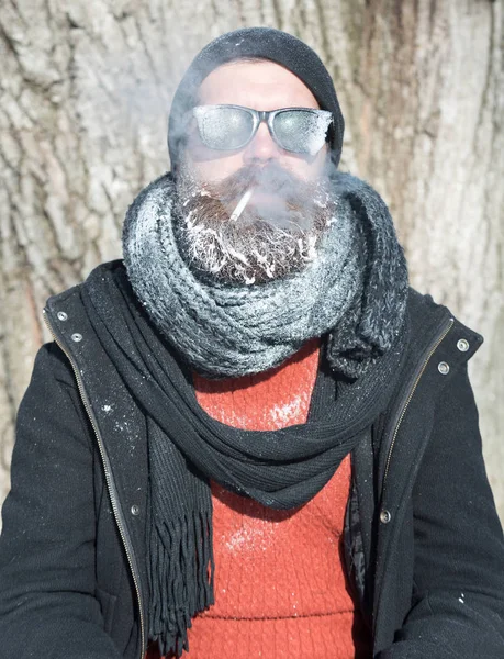 Przystojny facet z brodą pali papierosa. — Zdjęcie stockowe