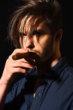 Ciddi sakallı adam puro içiyor.