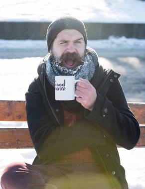 Göz kırpan adam bardaktan içer.