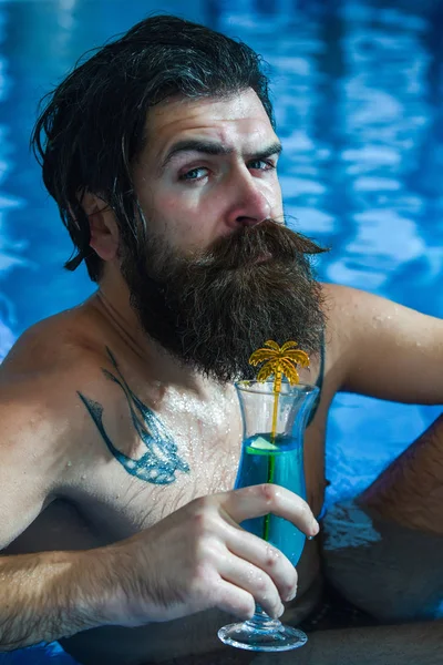 Мужчина пьет коктейль в бассейне — стоковое фото