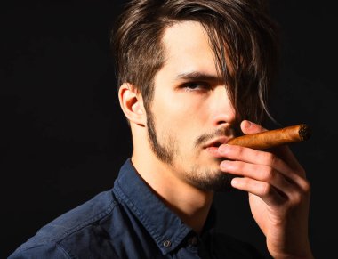 Ciddi sakallı adam puro içiyor.