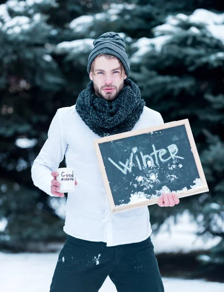 Handsome man with cup and blackboard in winter outdoor — Stock Photo, Image