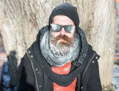 Yakışıklı sakallı adam sigara içiyor.