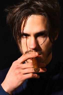 Ciddi sakallı adam puro içiyor.