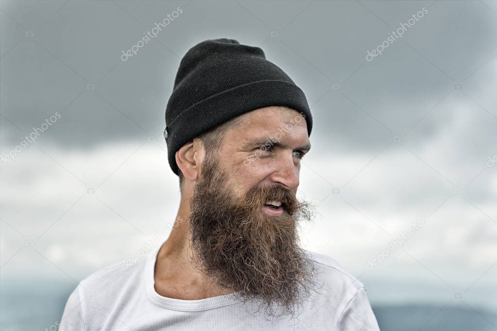 bearded handsome smiling man in hat on cloudy sky