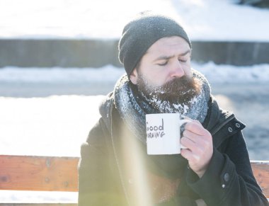Kaşlarını çatan adam bardaktan içer.