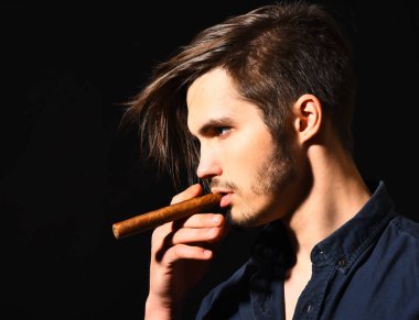 Ciddi sakallı adam puro içiyor.