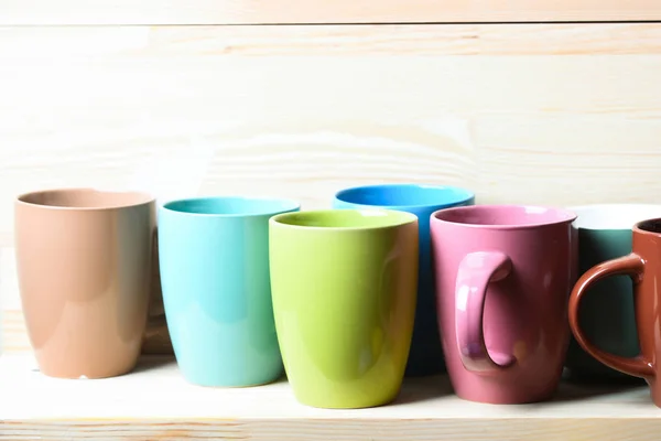 Bunte Tee- oder Kaffeetassen auf hölzernem weiß strukturiertem Hintergrund — Stockfoto