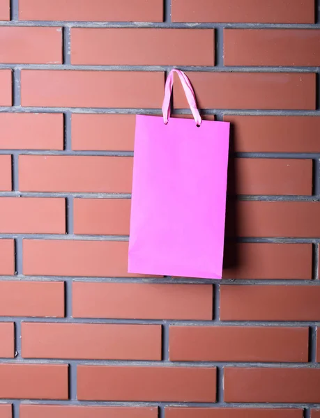 Saco de compras rosa na parede de tijolo marrom, espaço de cópia — Fotografia de Stock