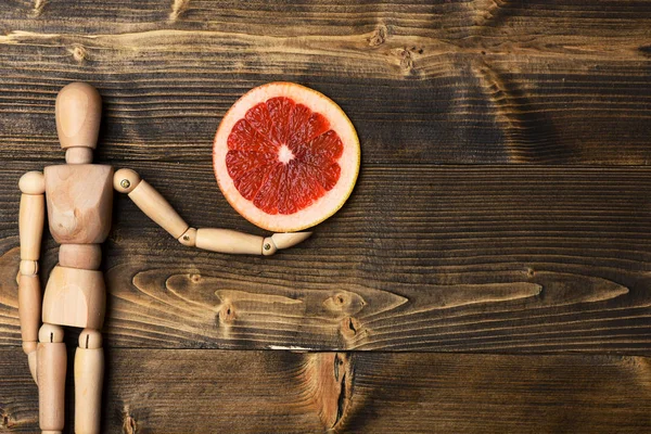 Boneco de madeira segurando fatias de toranja — Fotografia de Stock