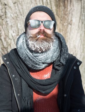 Yakışıklı sakallı adam sigara içiyor.