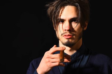 Sigara içen ciddi sakallı bir adam.