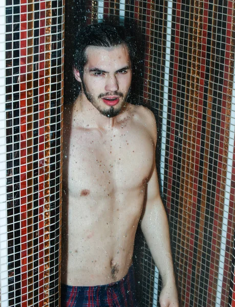 Handsome muscular sexy man washes in shower