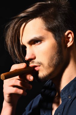 Ciddi sakallı adam puro içiyor.