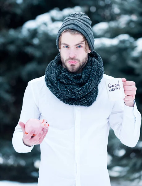 Красивый мужчина с копилкой и чашкой на открытом воздухе зимой — стоковое фото