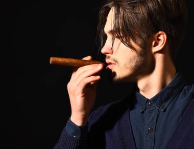 Ciddi sakallı adam puro içiyor.