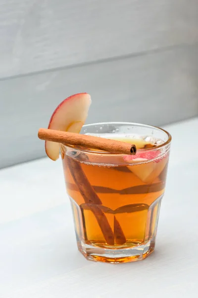 Glass with juice, pieces of apple and cinnamon — Stock Photo, Image