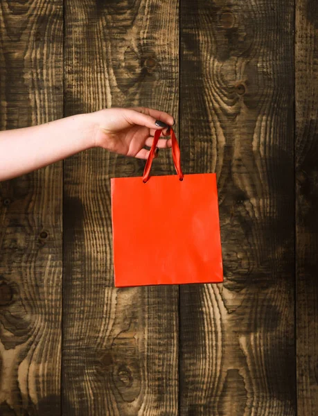 Sac à provisions orange rouge à la main féminine sur fond en bois — Photo
