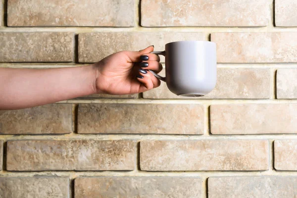 Chá azul ou xícara de café na mão na parede de tijolo — Fotografia de Stock