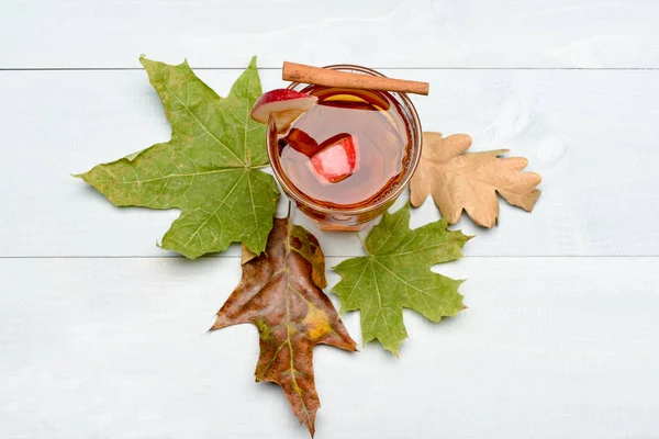 Vidro com suco, pedaços de maçã, canela, folhas — Fotografia de Stock