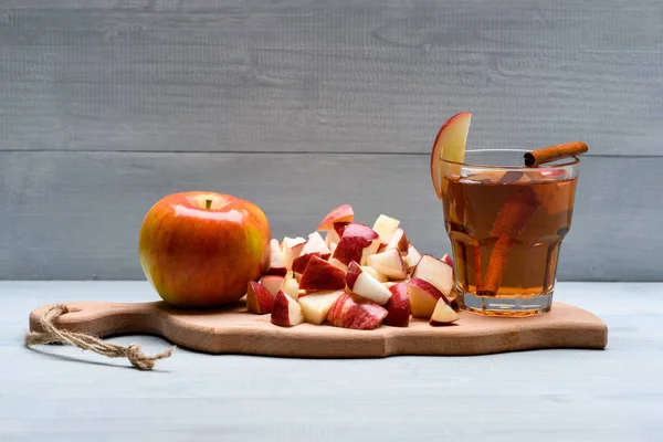 Cam suyu, elma parçaları, tarçın kesme tahtası üzerinde — Stok fotoğraf