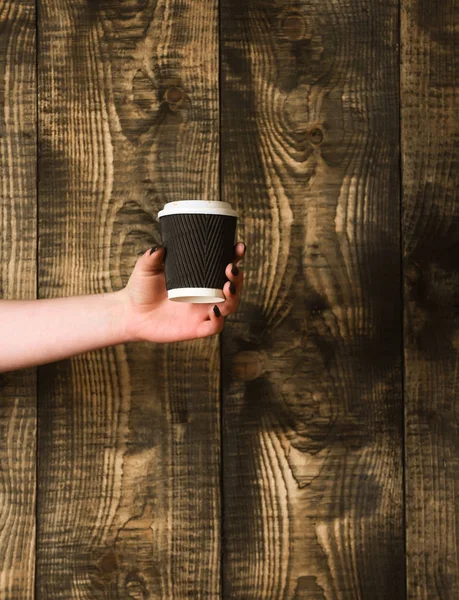 Paper or plastic coffee cup in hand on wooden background — Stock Photo, Image