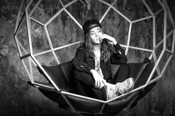Bonita mujer en gorra sentada en silla geométrica —  Fotos de Stock