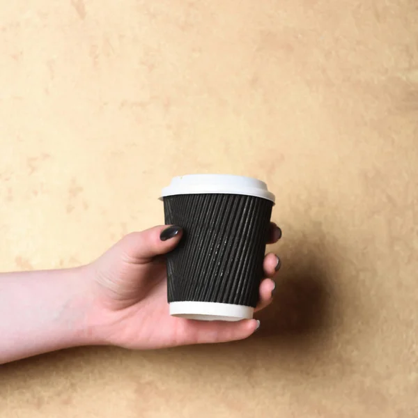 Papel ou copo de café de plástico na mão sobre fundo texturizado — Fotografia de Stock