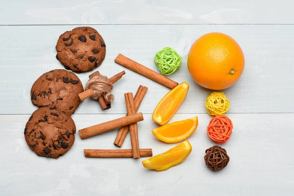 cinnamon, orange, chocolate cookies and decorative balls on wooden background