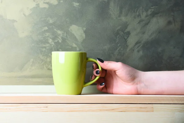 Green tea or coffee cup in hand on grey background — Stock Photo, Image