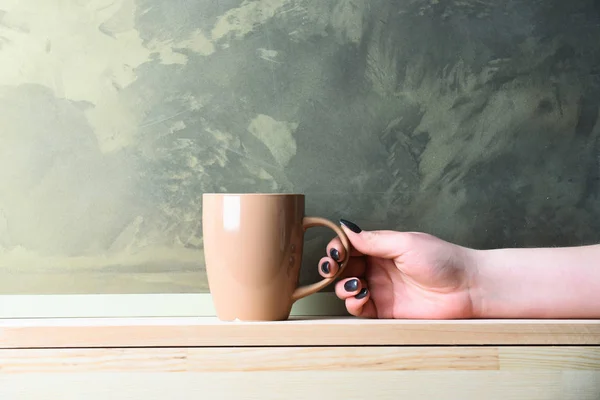 Thé beige ou tasse à café à la main sur fond gris — Photo