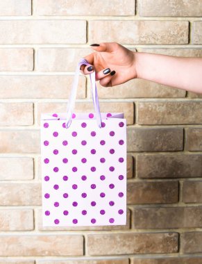 Beyaz benekli alışveriş çantası el tuğla duvar