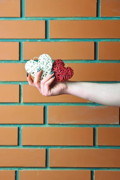 Corazón de San Valentín rosa en mano femenina en la pared de ladrillo — Foto de Stock