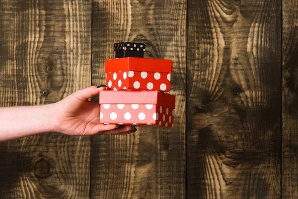 Boîte cadeau coloré tacheté à la main féminine sur fond en bois — Photo