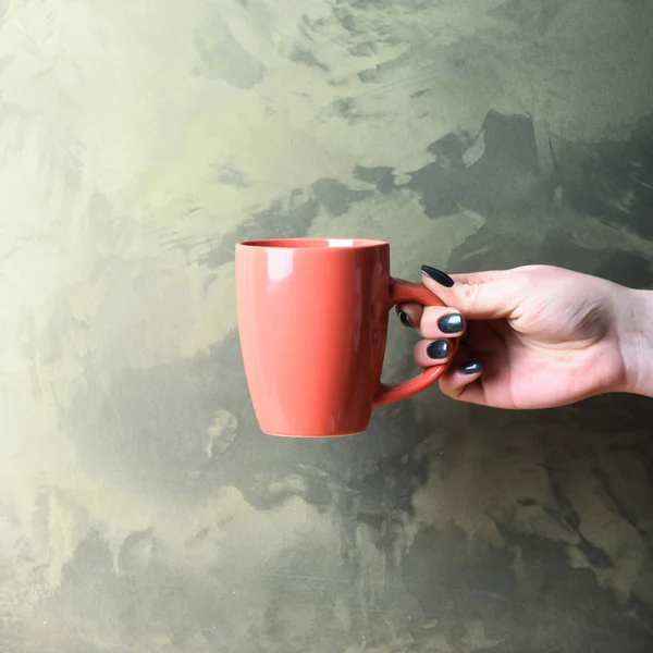 Pink tea or coffee cup in hand on textured background — Stock Photo, Image