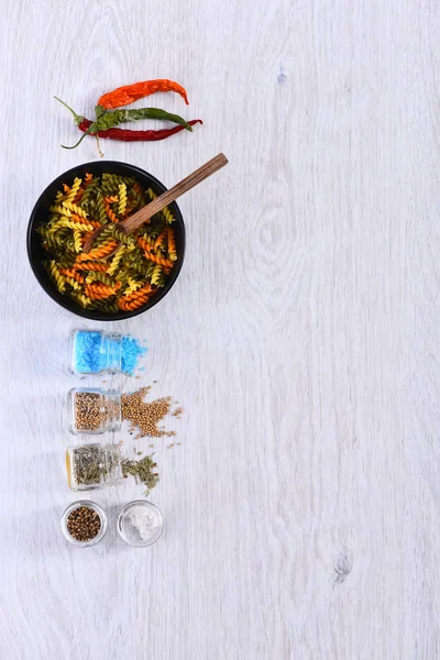 Deska s těstoviny, lžíce, koření ve sklenicích, chili pepper — Stock fotografie