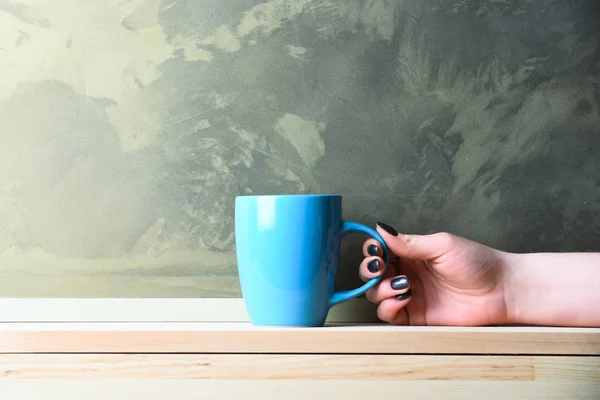 Té azul o taza de café en mano sobre fondo gris — Foto de Stock