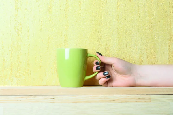 green tea or coffee cup in hand on yellow background
