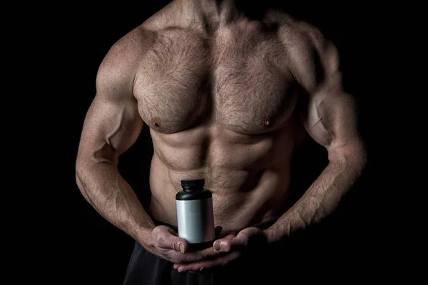 Красивый сексуальный спортсмен с мускулистым телом держит пластиковую банку или контейнер — стоковое фото