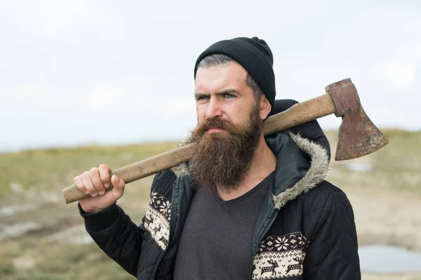 Barbudo guapo hombre serio con hacha oxidada en la cima de la montaña — Foto de Stock