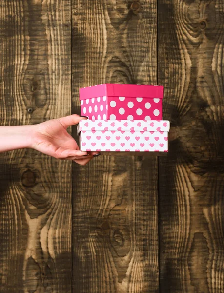 Caixa de presente manchado colorido na mão feminina sobre fundo de madeira — Fotografia de Stock