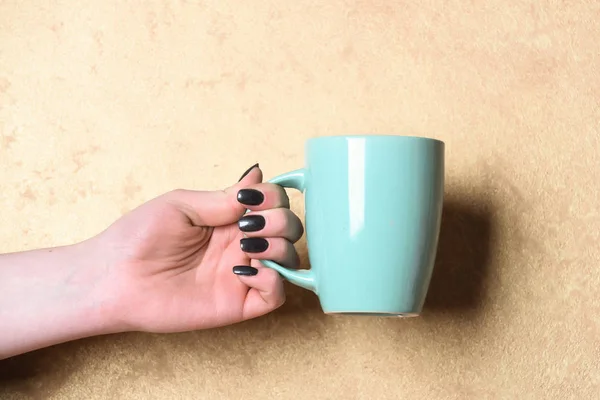 blue tea or coffee cup in hand on textured background